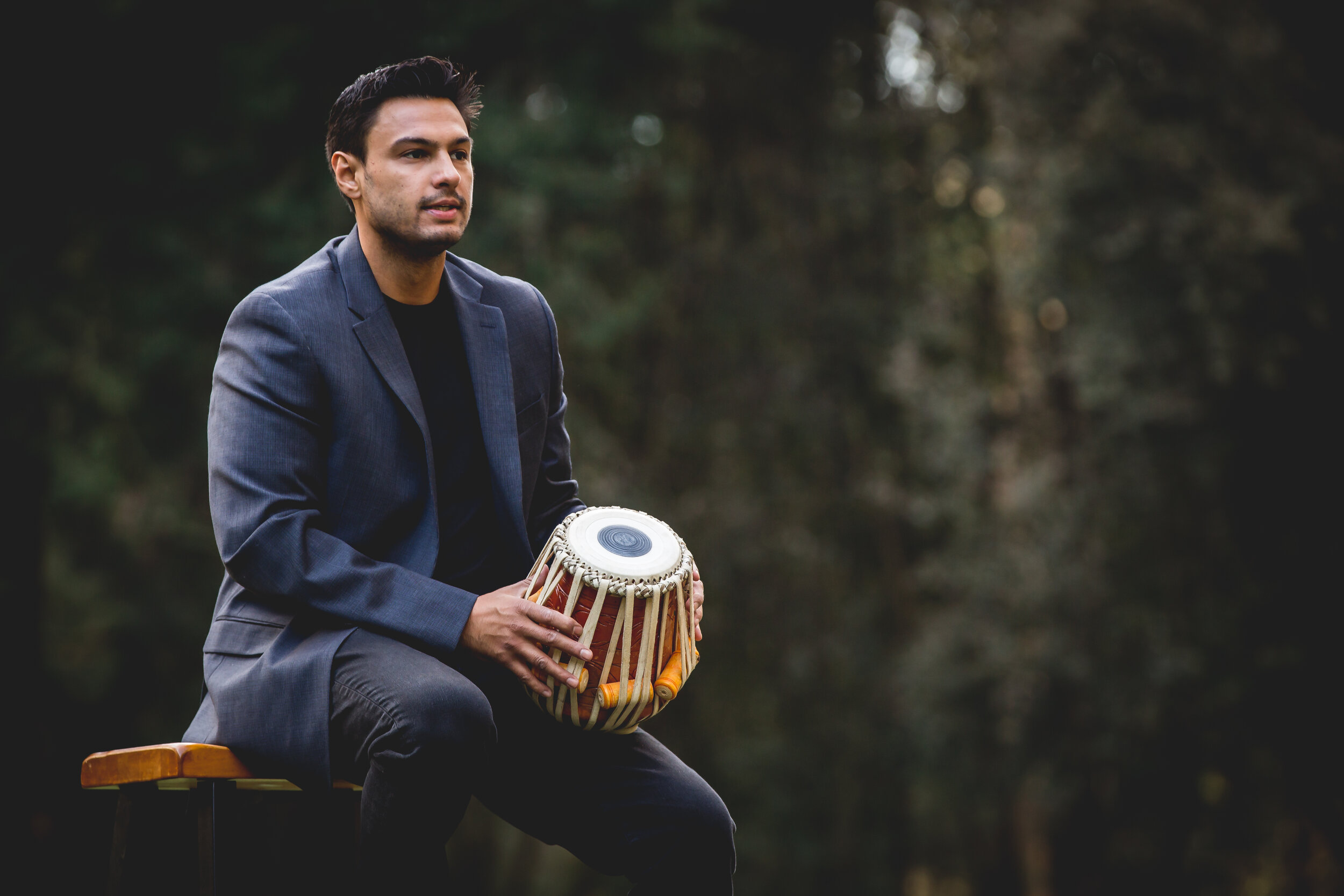 Nilan Chaudhuri seated outdoors with a dayan tabla resting on his knee